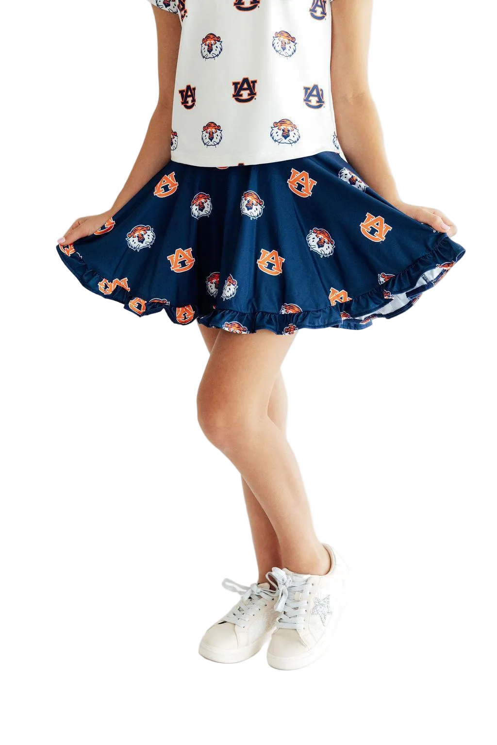 A child wearing a navy blue ruffled skirt with an orange and white tiger face pattern, paired with a white sleeveless top and white sneakers, shown from the chest down on a white background.